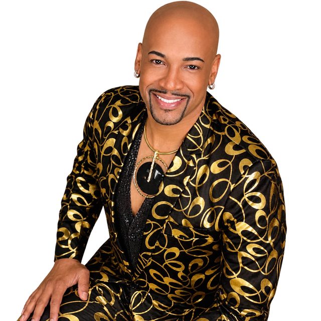 Antonio Edwards smiling in a black and gold suit